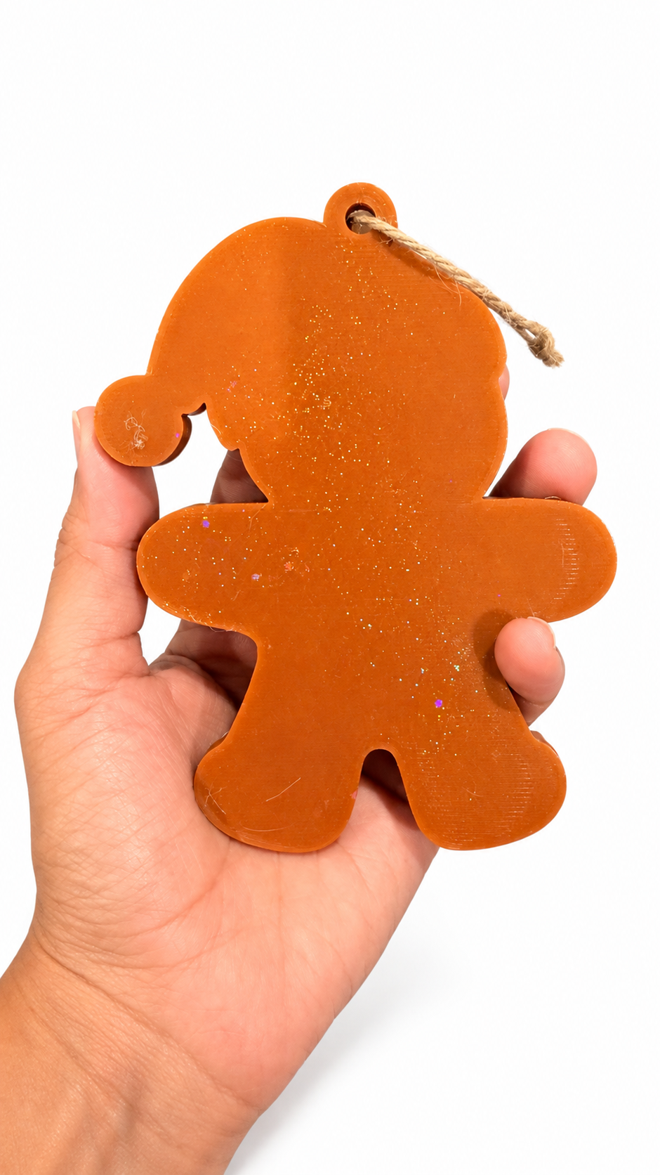Back of the 3D printed gingerbread ornament held in a hand, smooth sparkly brown finish with natural jute cord
